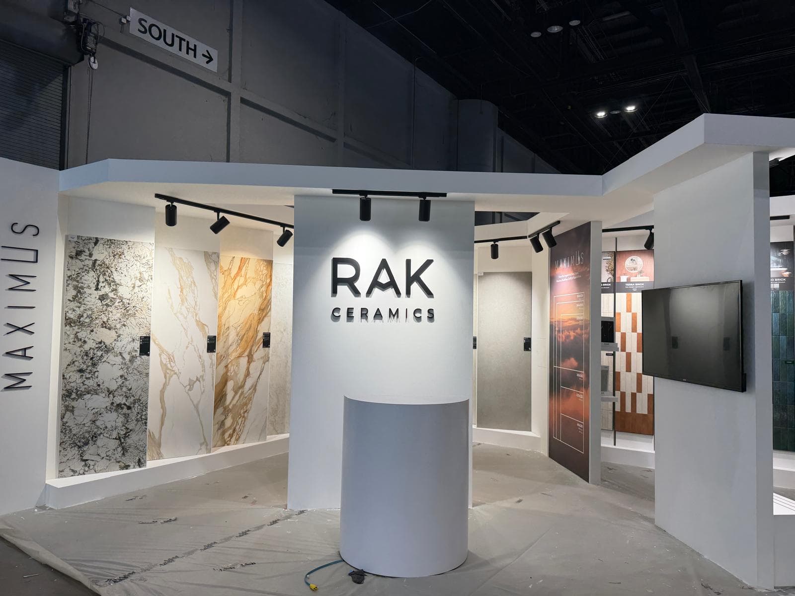 RAK Ceramics exhibition booth featuring large marble-effect tiles and a central white podium.
